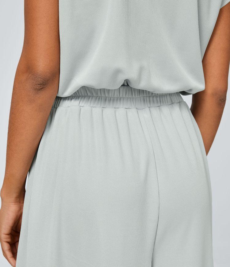 Jumpsuit™ - Tuta with V-shaped collar, short sleeve, side pocket with pieghe and wide leg, fluid wave pattern.